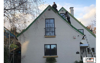 couvreurs en train de travailler sur une maison avec toit en pente