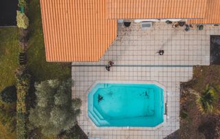 vue du ciel d'un toit incliné de maison avec terrasse et piscine