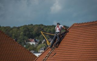 couvreur sur une toiture en tuiles à Marche-en-Fammenne